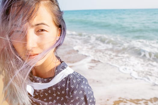 Portrait of young woman on background of sea, looking at camera.