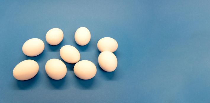 Nine white chicken eggs on blue background, enough space for textm minimal and easter concept. Good for cook recipes