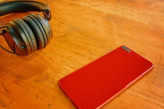 Wireless headphones and smartphone close-up. Modern everyday gadgets on wooden table. Concept of blogging, podcasting.