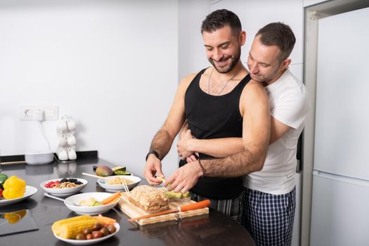 Gay couple cooking healthy vegan food together at home. Homosexual relationship concept.