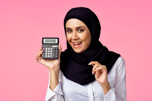 muslim woman with calculator and finance money pink background. High quality photo