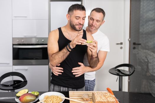 Gay couple cooking healthy vegan food together at home. Homosexual relationship concept.