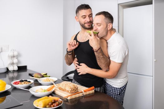 Gay couple cooking healthy vegan food together at home. Homosexual relationship concept.
