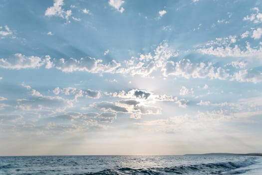 Beautiful blue sky with sunbeams among cumulus clouds over the sea.