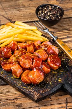 Currywurst Sausages street food served French fries on a wooden board. wooden background. Top view.