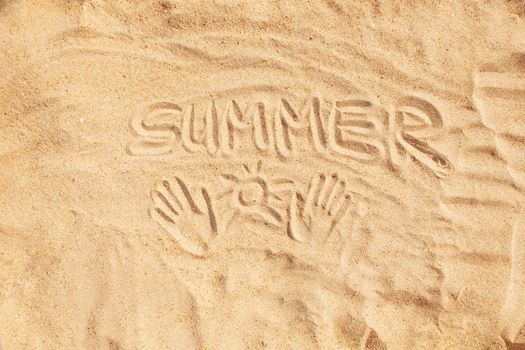Inscription word summer and hand prints on sand, concept of beach vacations.