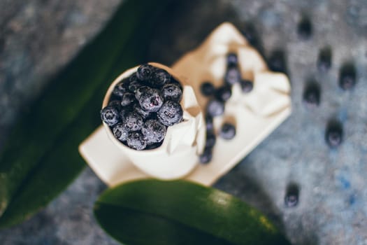 Fresh Blueberries in a bowl on dark background, top view. Juicy wild forest berries, bilberries. Healthy eating or nutrition.