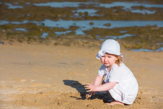 little girl playing with sand on the coast