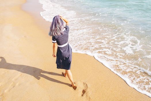Barefoot girl walking on sand beach near the sea, summer vacations.