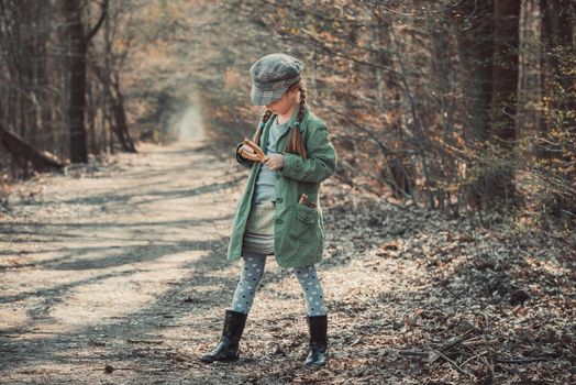 little girl playing with a slingshot in the woods, photo in vintage style