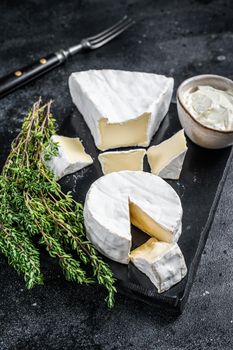 Cheese platter. Camembert, Brie, Gorgonzola and blue cream cheese with thyme. Black background. Top view.