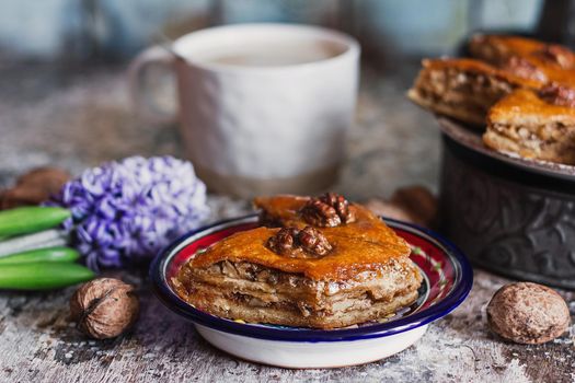 Assorted baklava. A Turkish ramadan arabic sweet dessert on a decorative plate, with coffee cup in the background. Middle eastern food baklava with nuts and honey syrup.