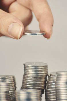 Womans hand put silver money coins to one of stacks. Concept of business planning and finance. Expenses and earnings. Alms and donations. Small savings.