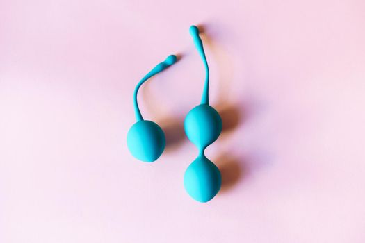 Set of three blue Kegel balls, Geisha balls in pink background.