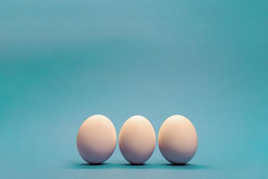 Three white eggs on light blue background, minimal Easter concept, enough space for text.