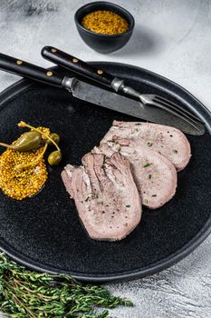 Veal or beef boiled tongue slices on a plate. White background. Top view.