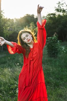 attractive woman in red dress posing in nature green grass. High quality photo