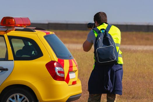 Man in yellow vest does plane spotting at the airport, close up