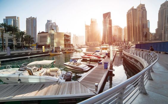 Panoramic view with modern skyscrapers and water pier of Dubai Marina at sunset, United Arab Emirates