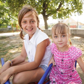Two sisters on the carousel at the playground
