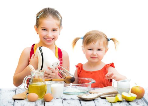 two little smiling sisters cooking isolated on a white background