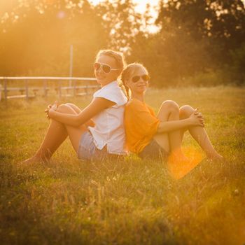 Two teenage girls have fun in the park. Two friends outdoor. Summwer people in glasses