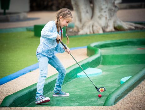 little girl playing golf outdoors