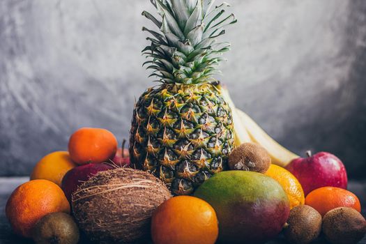 Colorful fresh tropical fruits on grey concrete background.