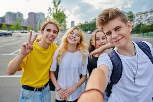Smiling group of teenagers taking selfie, happy four teens looking at camera, city urban background. Fun, friendship, lifestyle, leisure, summer, adolescence, students concept