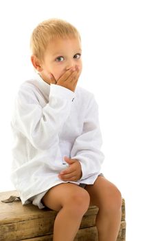 A cute little boy is sitting on an old chest. Isolated over white background.