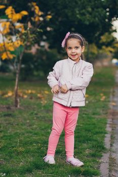 Young girl in a pink jacket and pink leggings in the park.