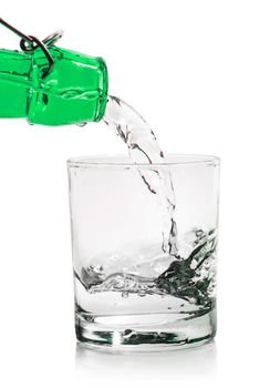 Glass with water pouring from a bottle isolated on a white background