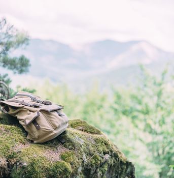 Backpack on cliff with moss in summer mountains outdoor.