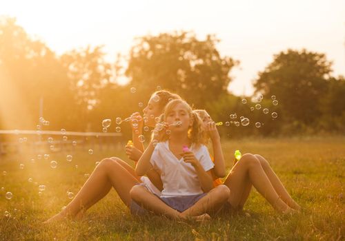 Three teenage girls have fun in the park. Two friends outdoor. Summer people doing bubbles