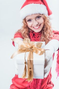 Christmas santa girl holds white giftbox with gold ribbon. Focus on the box
