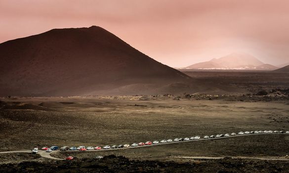 beautiful mountain landscape with a queue of cars in Timanfaya National Park in Lanzarote, Canary Islands