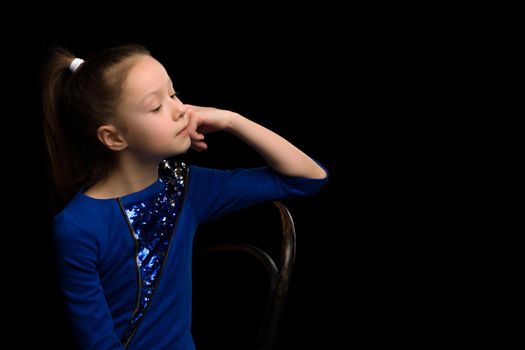 Beautiful studio portrait of a little girl in profile. On a black background.