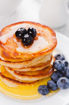 Pancakes with blueberry and honey on a white plate