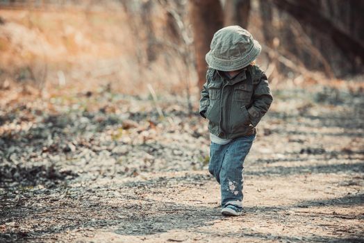 Funny little child walking in the woods, photo in vintage style