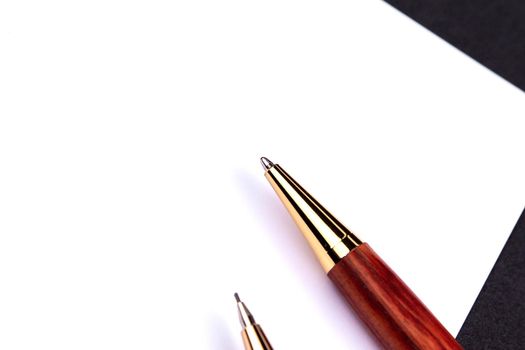 Luxury pen and mechanical pencil in wood and gold with a white sheet of paper.