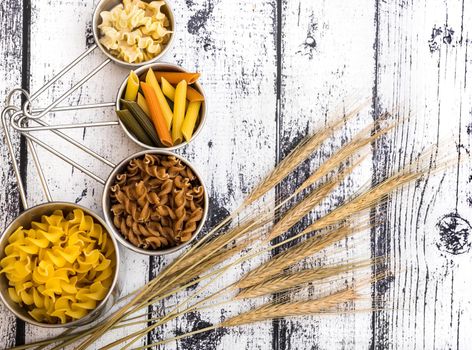 different kinds ofdifferent kinds of pasta on textured wooden table