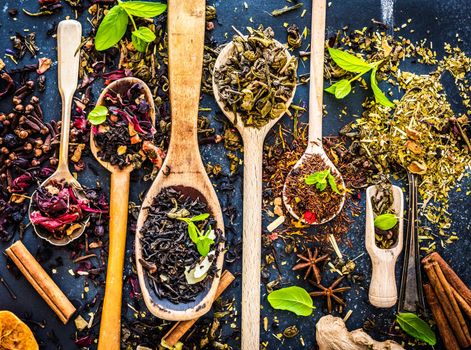 Virious kinds of tea in wooden spoons on black table