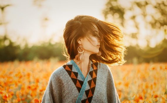 Boho stylish beautiful young woman relaxing in flower meadow on sunny summer day.