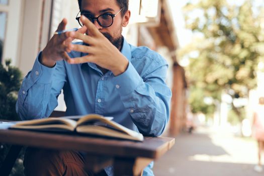 A man sits at a table in a summer cafe documents telephone communication. High quality photo