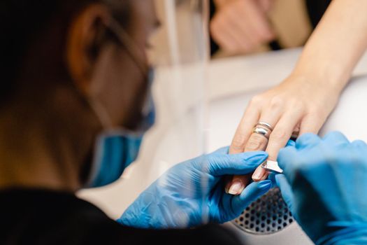 Aesthetician doing the manicure, filing the nails with a file to his client in a beauty center. Business and beauty concepts