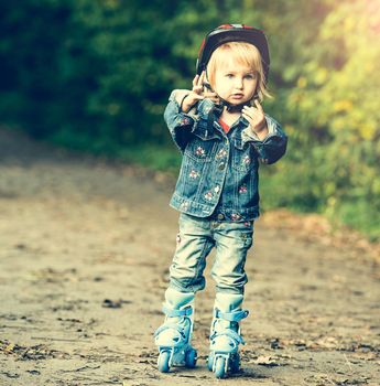 little girl on roller skates in helmet in the park