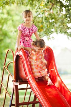 Two preschool girls on the slide at the playground