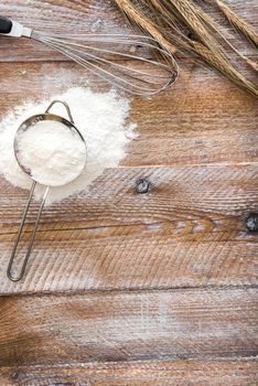 Sieve with flour on wooden board