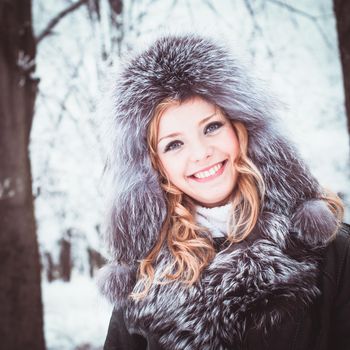 Woman is walking in park alley in winter