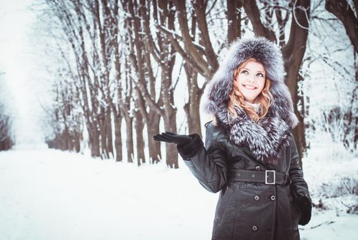 Woman is walking in park alley in winter